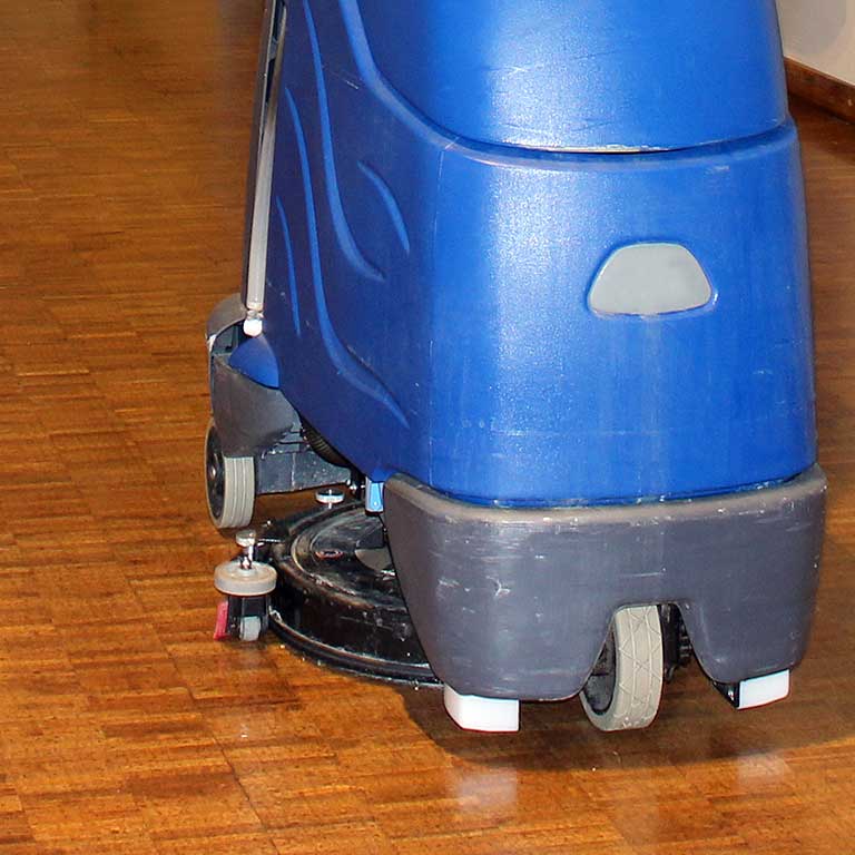 A floor cleaning machine cleans a wood floor.