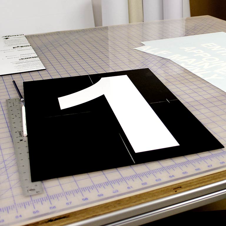 A large number 1 printed on a black sheet on a cutting mat