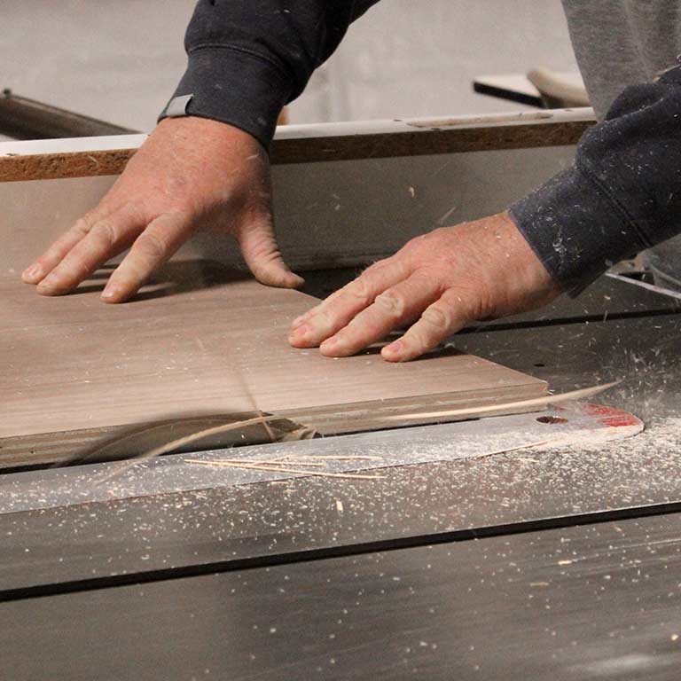 A person uses a table saw to cut wood.